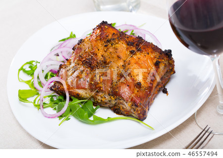 Tasty pork ribs baked under sauce, served with arugula and onion salad Tasty pork ribs baked under sauce, served with arugula and onion salad 46557494