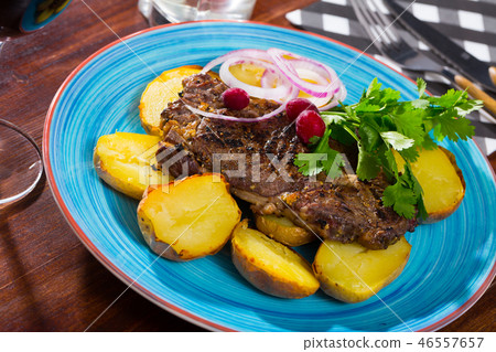 Beef steak with baked potatoes and sauce at plate with greens Beef steak with baked potatoes and sauce at plate with greens 46557657