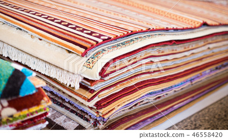 Stack of multicolored quality rugs at carpet shop Stack of multicolored quality rugs at carpet shop 46558420