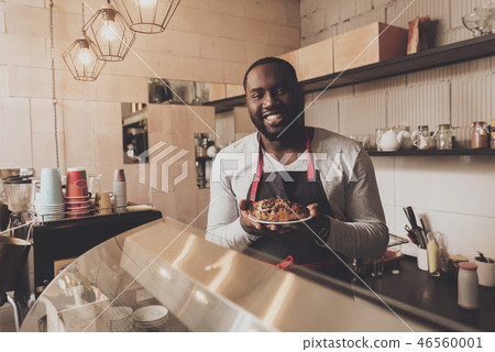 Male barista serves a croissant ordered to client Male barista serves a croissant ordered to client 46560001