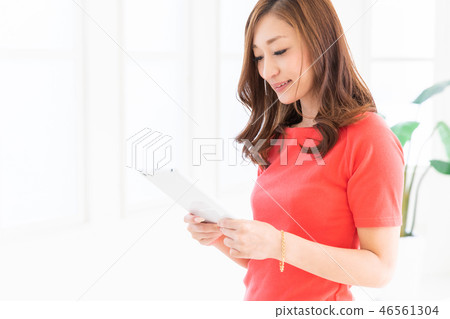 觀看一種片劑的婦女在屋子裡 觀看一種片劑的婦女在屋子裡 46561304
