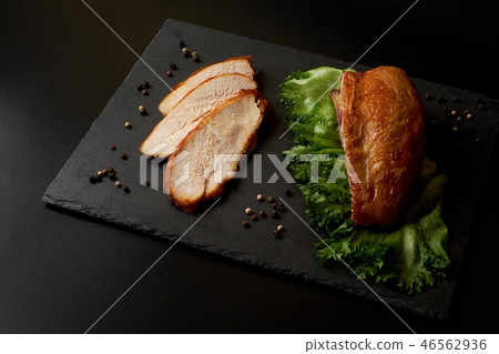 Roasted, sliced chicken breast on a black slate plate. Roasted, sliced chicken breast on a black slate plate. 46562936