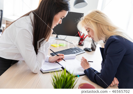 Two Girls Stand In The Office Bent Over Near Stock Photo