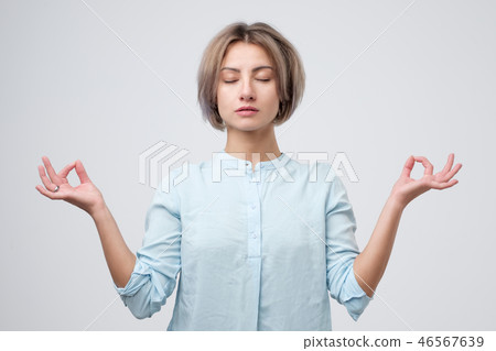 young woman meditating, holding her hands in yoga gesture, feeling calm and positive young woman meditating, holding her hands in yoga gesture, feeling calm and positive 46567639