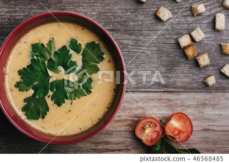 Vegetable vegetarian pumpkin cream soup with parsley in a bowl on a wooden table with tomatoes and 46568485