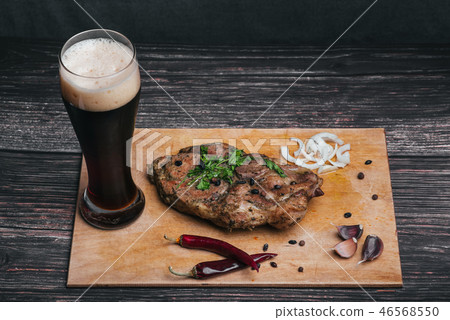 cooked pork with a glass of dark beer and other ingredients on a wooden Board cooked pork with a glass of dark beer and other ingredients on a wooden Board 46568550