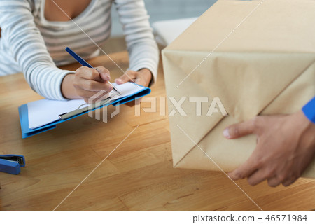 Woman signing for package delivery Woman signing for package delivery 46571984