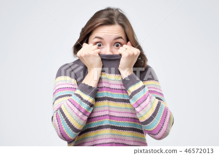 Girl pulling her trendy sweater over head having fun being childish disappearing in her clothes 46572013