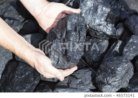 A man holding a piece of coal. 46573141