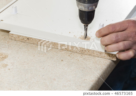 worker drills a hole when assembling furniture 46573165