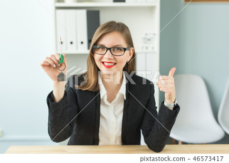 New home and real estate concept - Happy realtor woman giving you keys and showing thumb up New home and real estate concept - Happy realtor woman giving you keys and showing thumb up 46573417