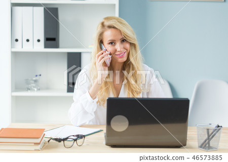 Working, business, technology and people concept - young woman watching in laptop and talking phone 46573885
