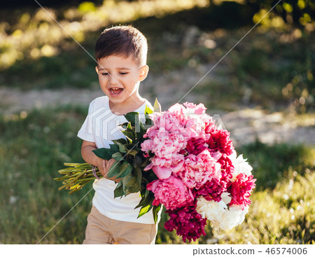 Small boy carries a large bouquet of peonies. 46574006