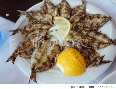 Small fried fish appetizer served with lemon 46574080