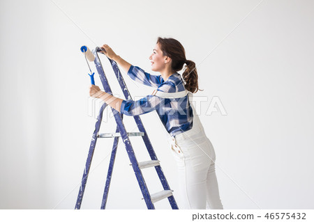 Repair, renovation, new home and people concept - Beautiful woman standing on the ladder during Repair, renovation, new home and people concept - Beautiful woman standing on the ladder during 46575432