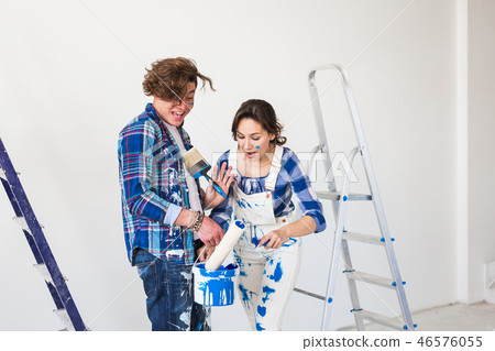 People, repair and relationship concept - Young funny couple doing renovation in new apartment 46576055