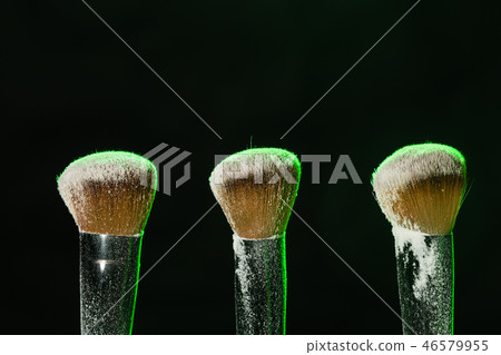 Make up, beauty and mineral cosmetic concept - brushes with green powder over the black background Make up, beauty and mineral cosmetic concept - brushes with green powder over the black background 46579955