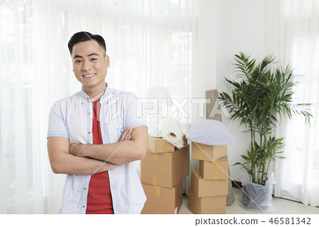 Smiling man with arms crossed in new flat 46581342