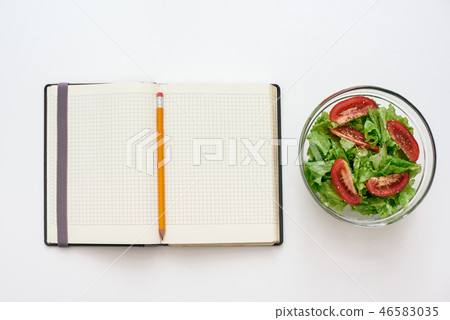 Healthy food preparing. Top view of cookbook for recipe, nearby salad Healthy food preparing. Top view of cookbook for recipe, nearby salad 46583035