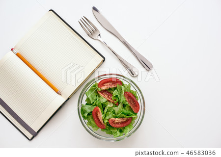 Healthy food preparing. Top view of cookbook for recipe, nearby salad Healthy food preparing. Top view of cookbook for recipe, nearby salad 46583036