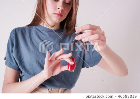 young cute teen girl paints nails isolated on grey young cute teen girl paints nails isolated on grey 46585819