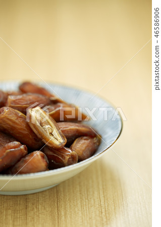 Sweet dried dates fruit in a bowl and on the table Sweet dried dates fruit in a bowl and on the table 46586906