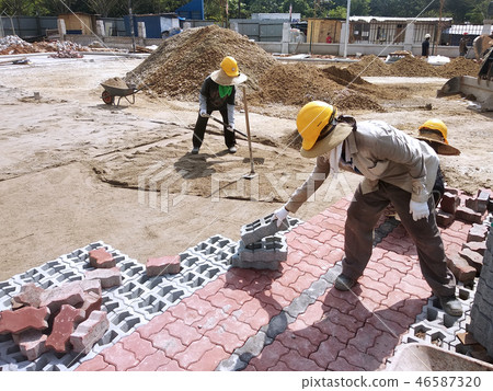 Workers installing concrete pavers block 46587320