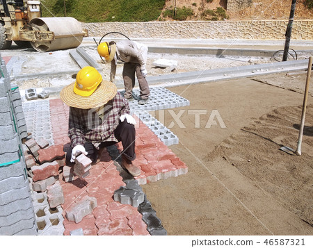 Workers installing concrete pavers block 46587321