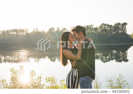 People, love and nature concept - Portrait of young beautiful couple embracing each other over water 46590091