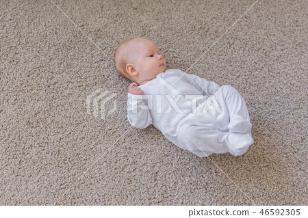 Childhood, infant and people concept - small baby lying on the floor 46592305