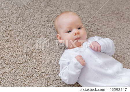 Childhood, infant and people concept - small baby lying on the floor 46592347