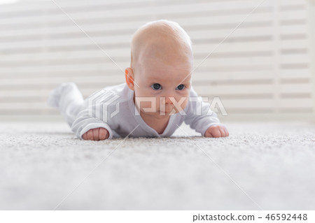Baby, childhood, people concept - Portrait of a crawling baby on the floor 46592448