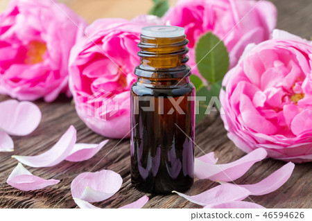 A bottle of rose essential oil with fresh roses A bottle of rose essential oil with fresh roses 46594626