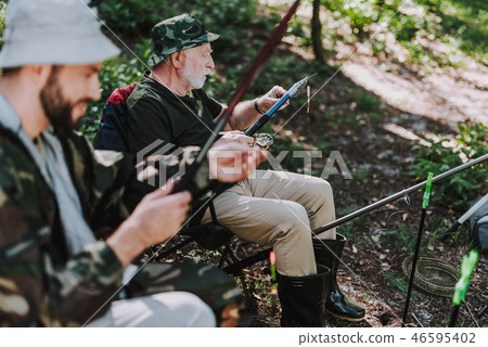 Elderly man putting bait on the hook while fishing 46595402