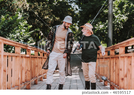 Full length of elderly angler and son standing on the wooden bridge 46595517