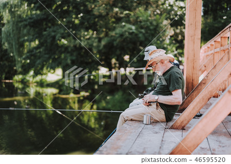 Pleasant aged man sitting on the wooden bridge 46595520