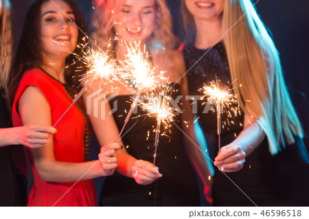 Celebrating with fun. Group of cheerful young women carrying sparklers. New year, holidays and party Celebrating with fun. Group of cheerful young women carrying sparklers. New year, holidays and party 46596518