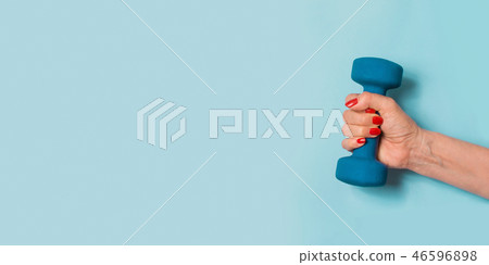 Female hand with blue dumbbell on blue. Sport.  46596898