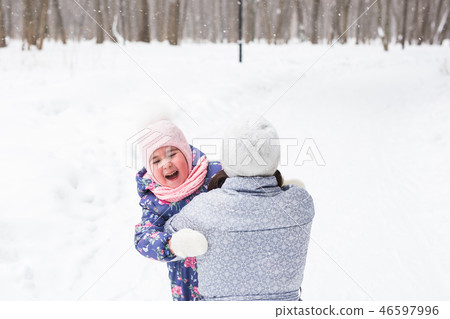 Family, childhood and nature concept - Young mother hug little daughter in the winter park 46597996