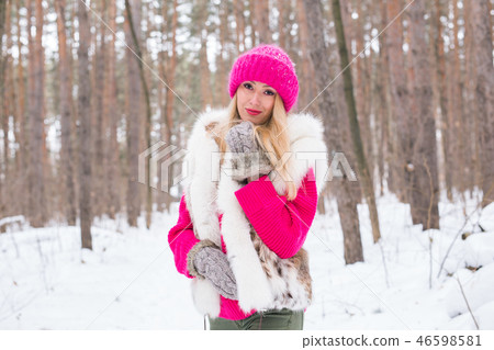 Beauty, nature and people concept - beautiful blond woman walking in pink hat and sweaters in winter Beauty, nature and people concept - beautiful blond woman walking in pink hat and sweaters in winter 46598581
