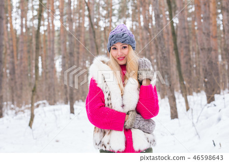 Nature, fashion and people concept - Young attractive blond woman posing in the winter park. Nature, fashion and people concept - Young attractive blond woman posing in the winter park. 46598643