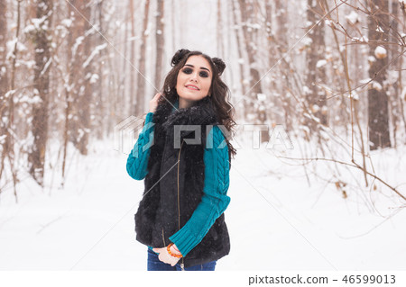 Winter, season and people concept - Young pretty woman walking in snowy park 46599013