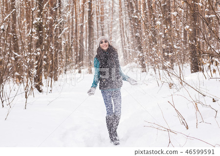 Happy young woman plays with a snow at snowy forest outdoor Happy young woman plays with a snow at snowy forest outdoor 46599591