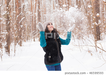 Season, leisure and people concept - young woman is happy and throwing snow in the winter nature Season, leisure and people concept - young woman is happy and throwing snow in the winter nature 46599593