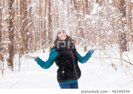 Season, leisure and people concept - young woman is happy and throwing snow in the winter nature Season, leisure and people concept - young woman is happy and throwing snow in the winter nature 46599594
