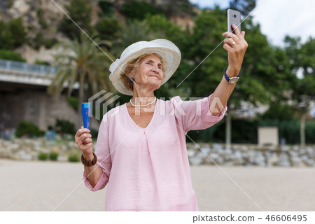 Mature woman taking selfie on beach 46606495