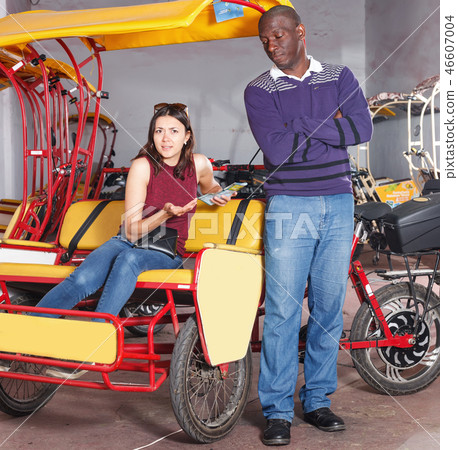 Dissatisfied woman talking with African-American man driver of rickshaw Dissatisfied woman talking with African-American man driver of rickshaw 46607004