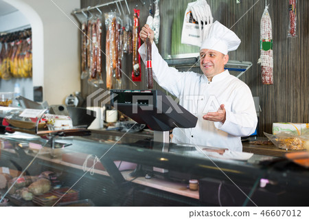 Salesman offering different sausages in market 46607012