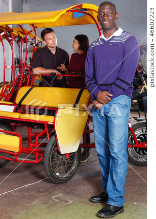 Confident cheerful African-American man recommending traveling with rickshaw Confident cheerful African-American man recommending traveling with rickshaw 46607223