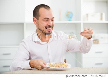 Positive young man eating porridge 46607518
